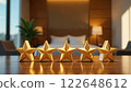 Five golden stars sit on a wooden table against a blurred hotel bedroom background, representing a top rating. Concept of excellence. 122648612