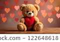 A plush toy bear holding a red heart with blurred heart lights in the background. Concept of affection. 122648618