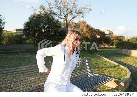 Woman Doctor Sits Wearily on a Bench Woman Doctor Sits Wearily on a Bench 122648957