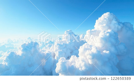 A serene and expansive view of a vibrant blue sky dotted with fluffy white clouds. The daylight radiates an inviting atmosphere, creating a peaceful landscape above. 122650389
