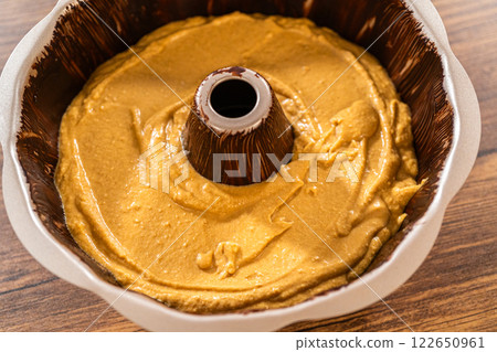 Pouring the gingerbread cake batter into the greased bundt cake pan, ready for a delightful caramel frosting. 122650961