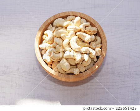 Cashew nuts in wooden bowl on white table with sunshine. Healthy food. Cashew nuts in wooden bowl on white table with sunshine. Healthy food. 122651422