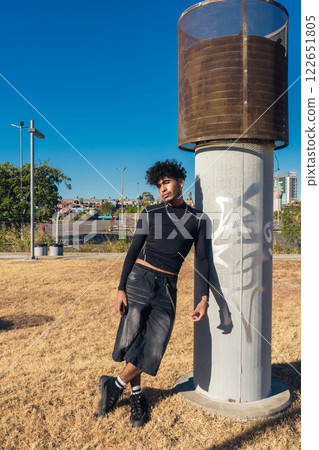 Young Hispanic African man leaning on a ventilation column outside. 122651805