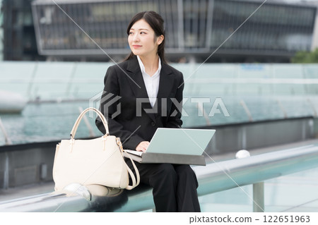 名古屋榮市 OASIS21 水上太空船，一位微笑的女商人正在戶外看著筆記型電腦 122651963