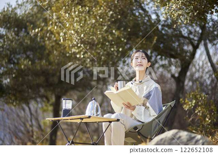 一位女子在冬日的樹林裡讀書。 一位女子在冬日的樹林裡讀書。 122652108