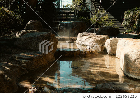Hot spring overflowing from a large rock 122653229