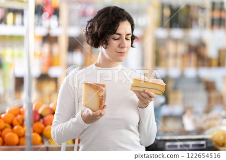 Adult woman choosing cheese in grocery store Adult woman choosing cheese in grocery store 122654516