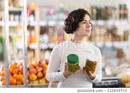 Adult woman choosing olives in grocery store Adult woman choosing olives in grocery store 122654554