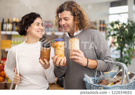 In store, couple near counter are looking at canned beans and lentils In store, couple near counter are looking at canned beans and lentils 122654683