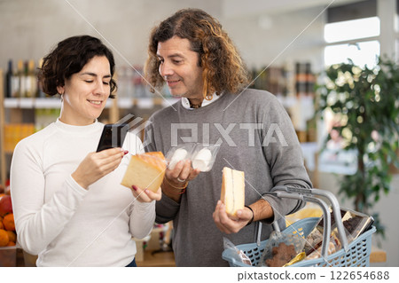 Spouses get acquainted with food, scan QR code, take reading cheese label using phone camera 122654688