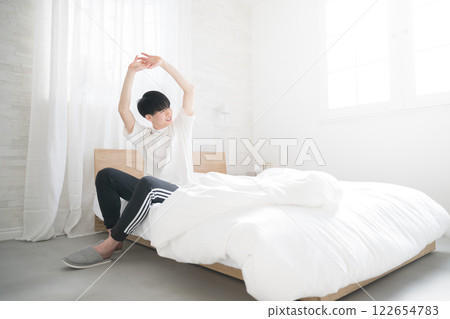 Wide-angle shot of a young man waking up in bed bathed in the morning sun. I slept well. Wide-angle shot of a young man waking up in bed bathed in the morning sun. I slept well. 122654783