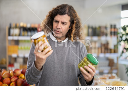 Adult man choosing olives in grocery store Adult man choosing olives in grocery store 122654791