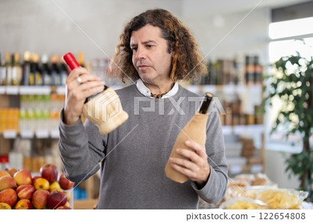 Shopping in produce supermarket - male buyer makes choice bottle of wine 122654808