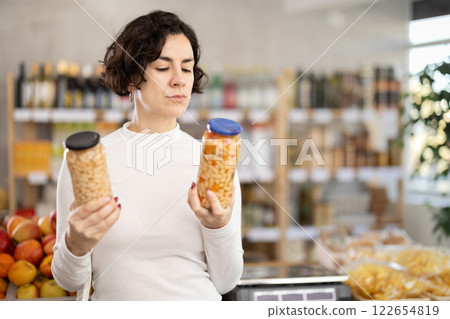 In store, customers near counter are looking at canned beans 122654819