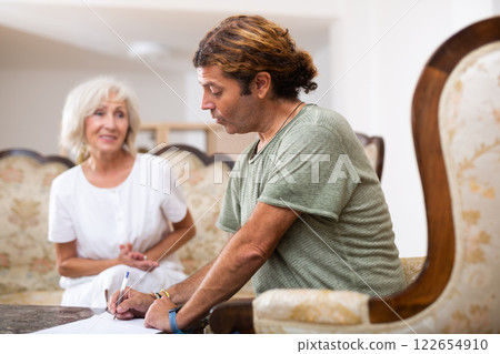 Mature woman and man doing paperwork together Mature woman and man doing paperwork together 122654910