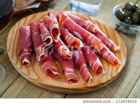 Spanish tapas - rolls of jamon serrano served on wooden board 122654918