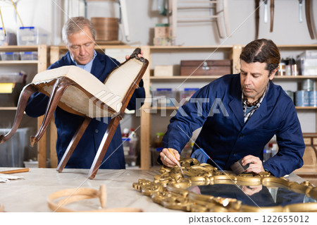 employees restore antique chair with twisted legs and mirror in massive carved wooden frame 122655012