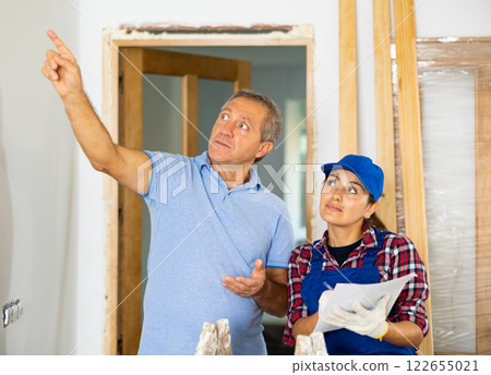 Woman repairer discussing repair works with man builder 122655021