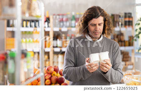 man chooses a package of yogurt man chooses a package of yogurt 122655025