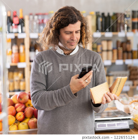 man scans a package of cheese on his phone 122655124