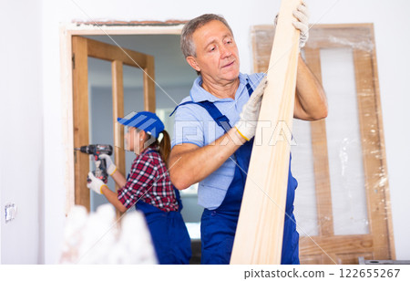 Skillful man builder carrying wooden planks in apartment Skillful man builder carrying wooden planks in apartment 122655267