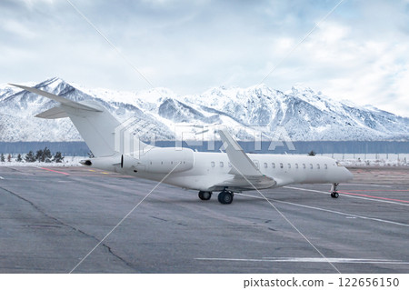 White luxury executive aircraft on airport in winter on the background of high picturesque snow capped mountains 122656150