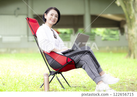 Workcation: Middle-aged woman working in the park 122656715