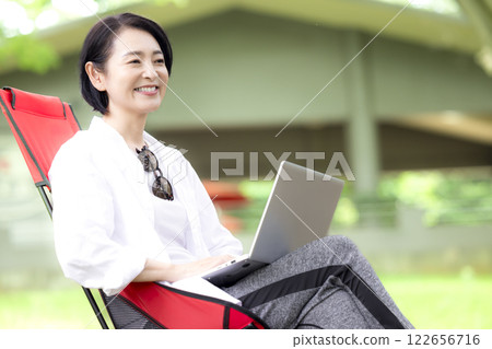 Workcation: Middle-aged woman working in the park 122656716