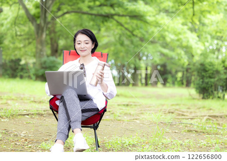Workcation: Middle-aged woman working in the park 122656800