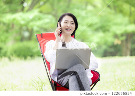 Workcation: Middle-aged woman working in the park Workcation: Middle-aged woman working in the park 122656834