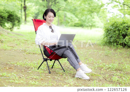 Workcation: Middle-aged woman working in the park Workcation: Middle-aged woman working in the park 122657126