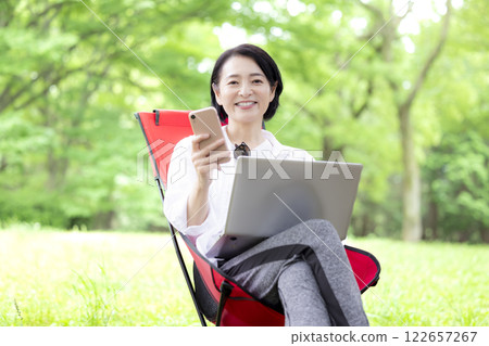 Workcation: Middle-aged woman working in the park Workcation: Middle-aged woman working in the park 122657267