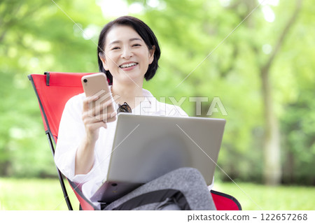 Workcation: Middle-aged woman working in the park Workcation: Middle-aged woman working in the park 122657268