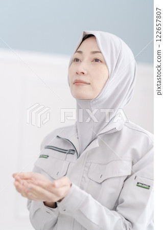 A middle-aged woman in work clothes praying in the company's prayer room 122657807