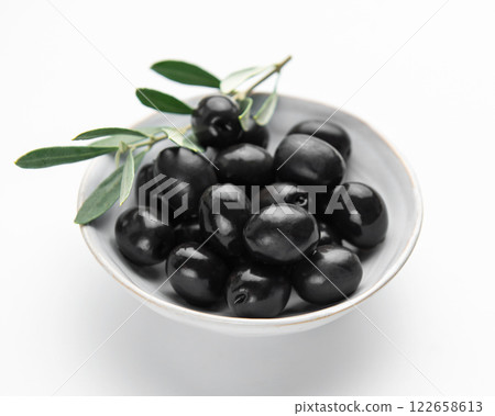 Black olives with leaves in a bowl on white background Black olives with leaves in a bowl on white background 122658613