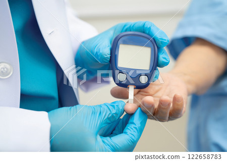 Asian doctor using digital glucose meter for check sample blood sugar level to treatment diabetes. Asian doctor using digital glucose meter for check sample blood sugar level to treatment diabetes. 122658783