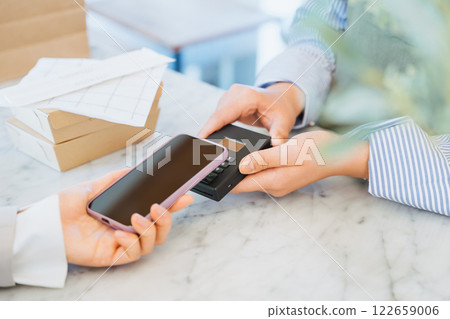 A woman pays for takeaway food purchased at a store by tapping her smartphone 122659006