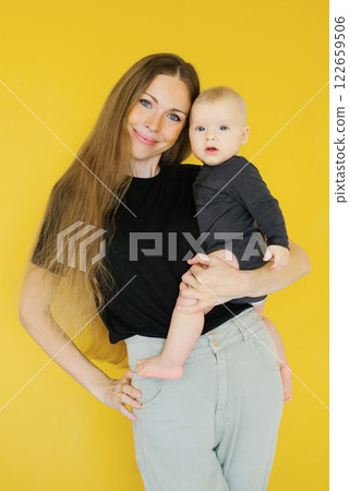 Young woman is holding boy baby in her arms. Warm and loving moment between mother 122659506