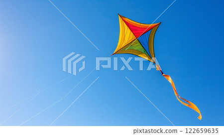 A colorful kite soars in the blue sky, symbolizing freedom and joy with its vibrant, graceful dance. 122659635