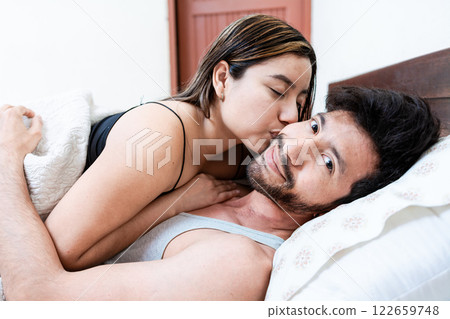 Woman in bed kissing her husband on the forehead. Wife in bed kissing husband on the forehead 122659748