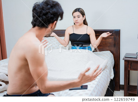 Upset wife with husband in bedroom bed, Young couple arguing in bed room. Concept of couple problems in bed, Husband fighting with his wife in bed Upset wife with husband in bedroom bed, Young couple arguing in bed room. Concept of couple problems in bed, Husband fighting with his wife in bed 122659749
