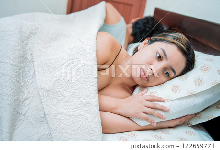 Upset couple sleeping on their backs. Young couple arguing and sleeping apart. Concept of couple problems in bed. Unhappy couple in bed sleeping apart 122659771