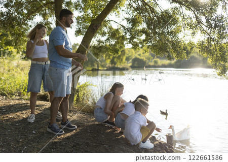 Family enjoying a relaxing day by the lake Family enjoying a relaxing day by the lake 122661586