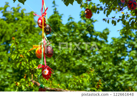 Festive bunch of colorful painted Easter eggs on green spring tree Festive bunch of colorful painted Easter eggs on green spring tree 122661648