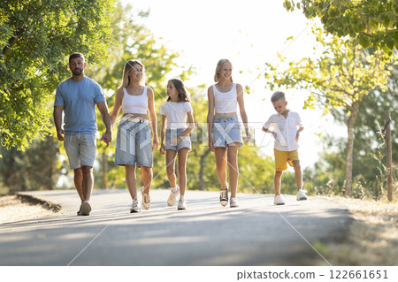 Family enjoying a leisurely walk in nature Family enjoying a leisurely walk in nature 122661651