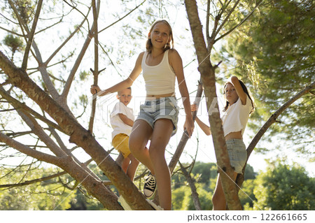 Children climbing tree enjoying summer vacation together Children climbing tree enjoying summer vacation together 122661665