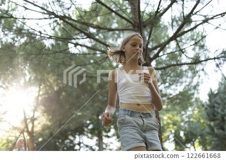 Young girl walking in a pine forest during golden hour Young girl walking in a pine forest during golden hour 122661668