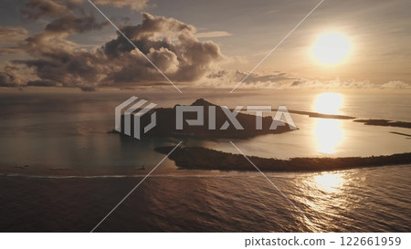 Perfect nature landscape, sunset tropical island under bright colorful orange sky, coral reef lagoon. Travel destination background. Amazing summer vacation to French Polynesia. Drone aerial view shot 122661959