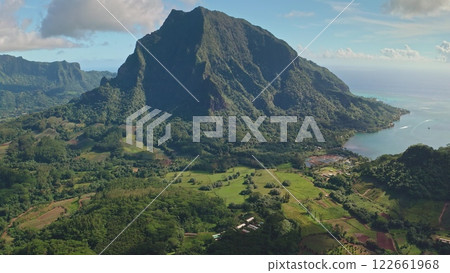 Aerial view revealing stunning beauty of Moorea, French Polynesia, with mount Rotui towering over green hills landscapes and tranquil turquoise water. Wild travel destination, remote nature paradise Aerial view revealing stunning beauty of Moorea, French Polynesia, with mount Rotui towering over green hills landscapes and tranquil turquoise water. Wild travel destination, remote nature paradise 122661968