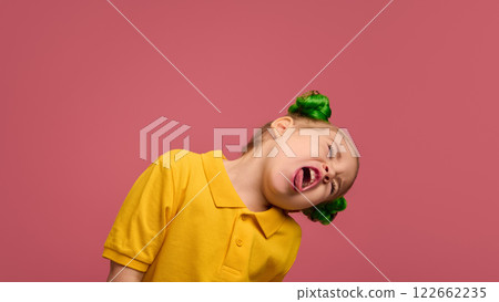 Portrait of playful child, preschool girl in yellow shirt and braided buns hairstyle emotionally making funny faces against pink studio background. Portrait of playful child, preschool girl in yellow shirt and braided buns hairstyle emotionally making funny faces against pink studio background. 122662235